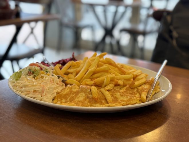 A large oval plate of chips with chicken and salad on a wooden table